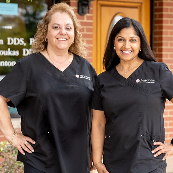 Dr. Jain and Dr. Sotiria smiling together in front of Pearly Whites dental office